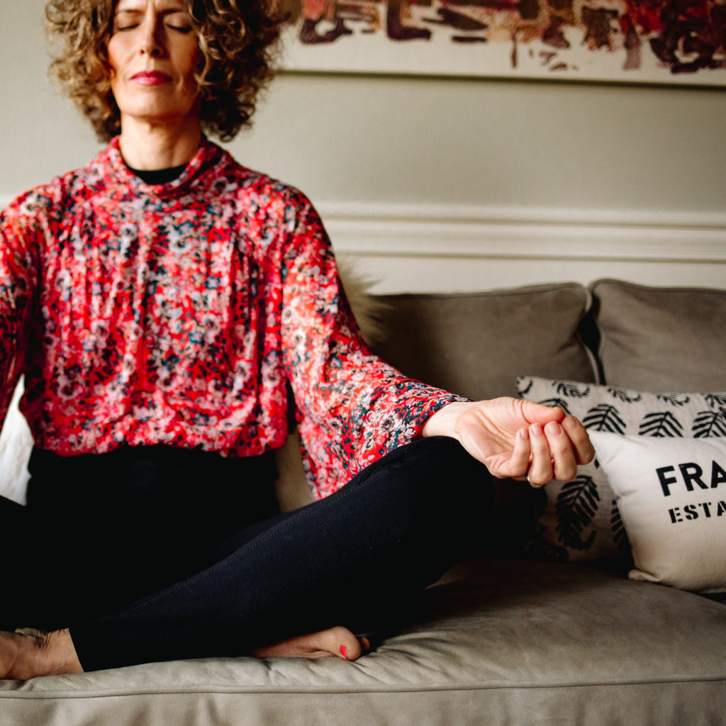 Woman in red shirt sitting on couch meditating