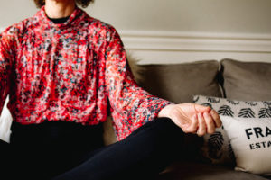 Woman in red shirt sitting on couch meditating