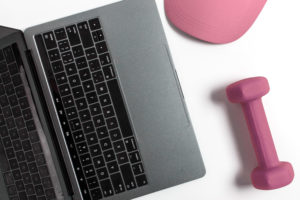 Pink hat pink dumbells laptop and headphones on desk