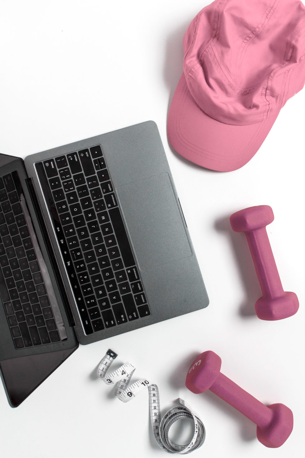 Pink hat pink dumbells laptop and headphones on desk