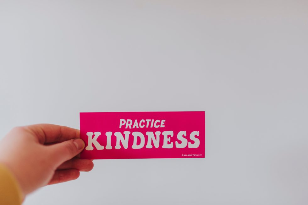 Woman holding fuscia sign Practice Kindness