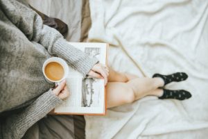 woman holding book and a cup of coffee